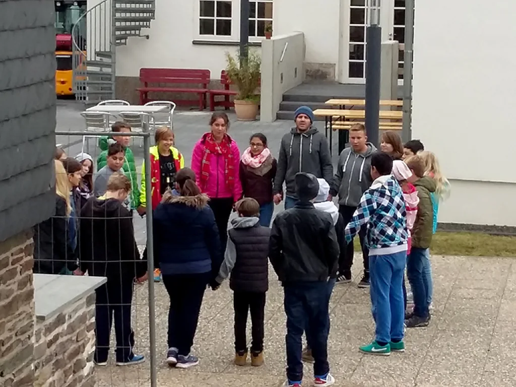 Gruppe steht im Kreis auf dem Hof der Jugendherberge.